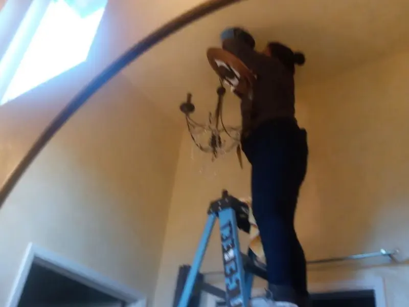 Electrician installing a chandelier in a New River residence